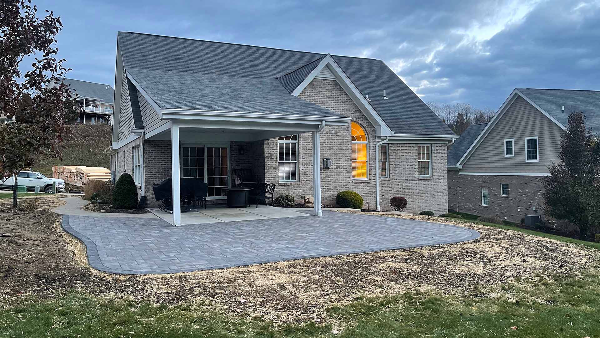 Curved paver patio under a covered porch at dusk