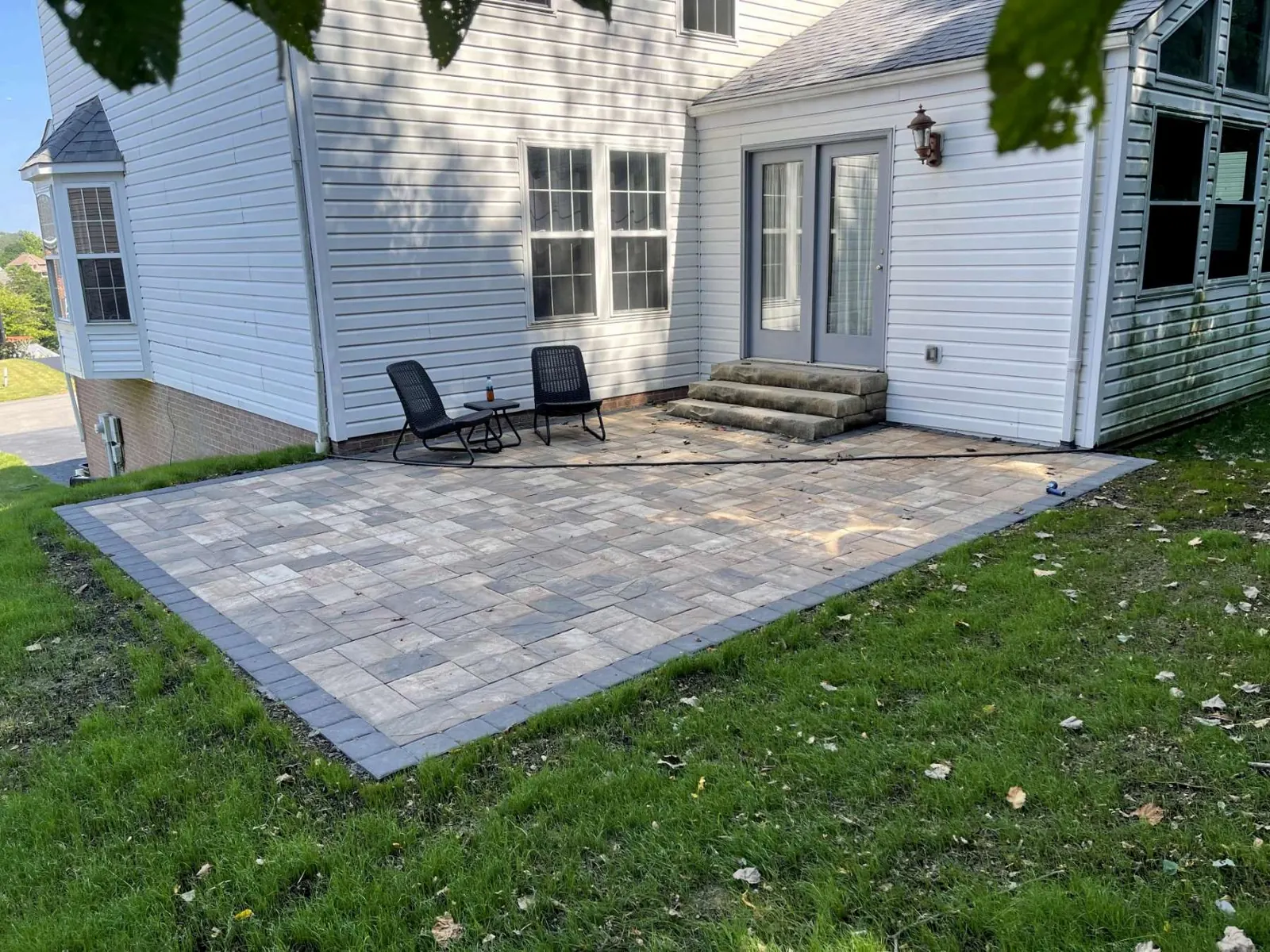 Large rectangular paver patio with a darker border paver beside a house