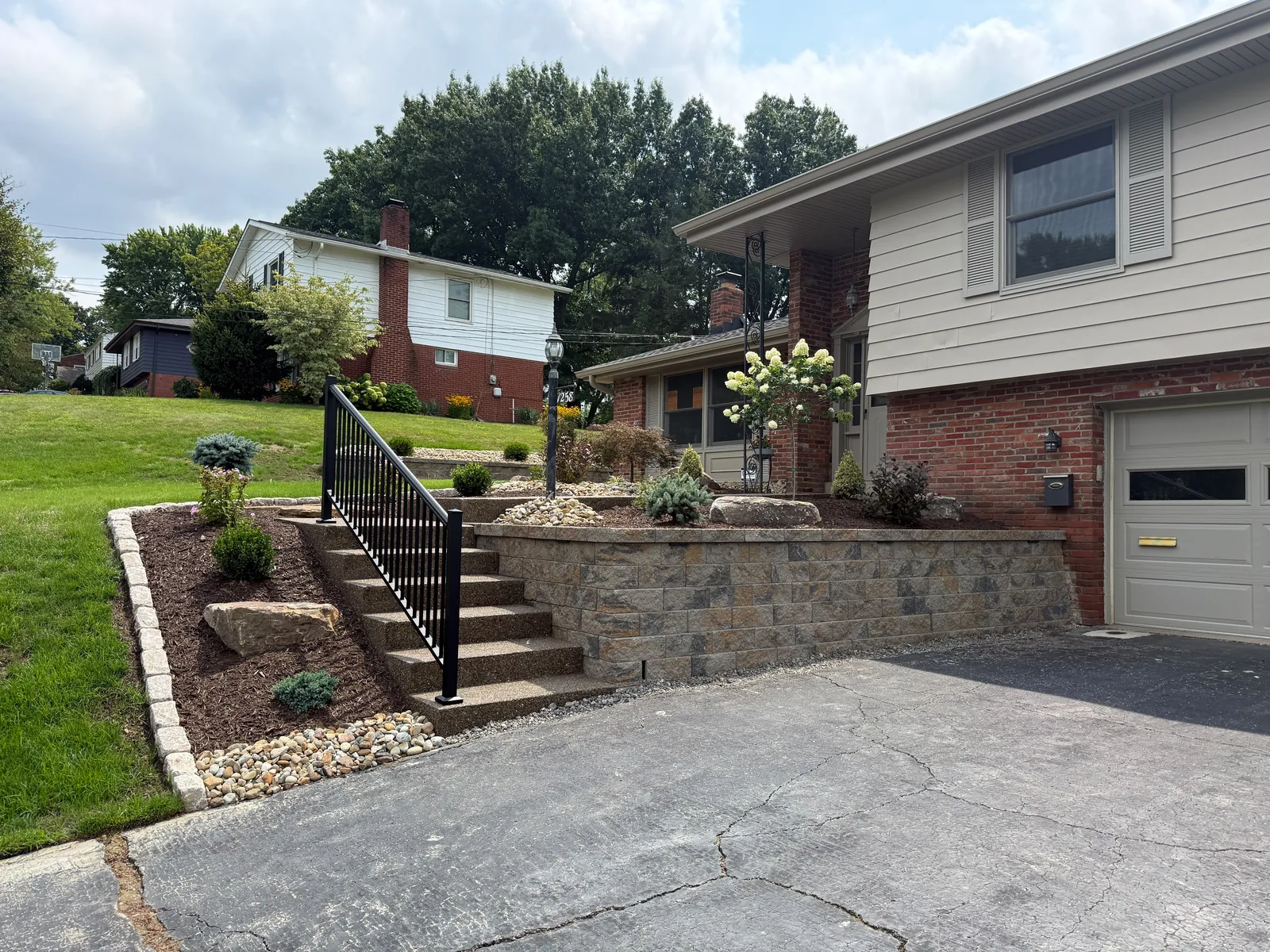New front steps with a black railing beside the Versa-Lok driveway wall