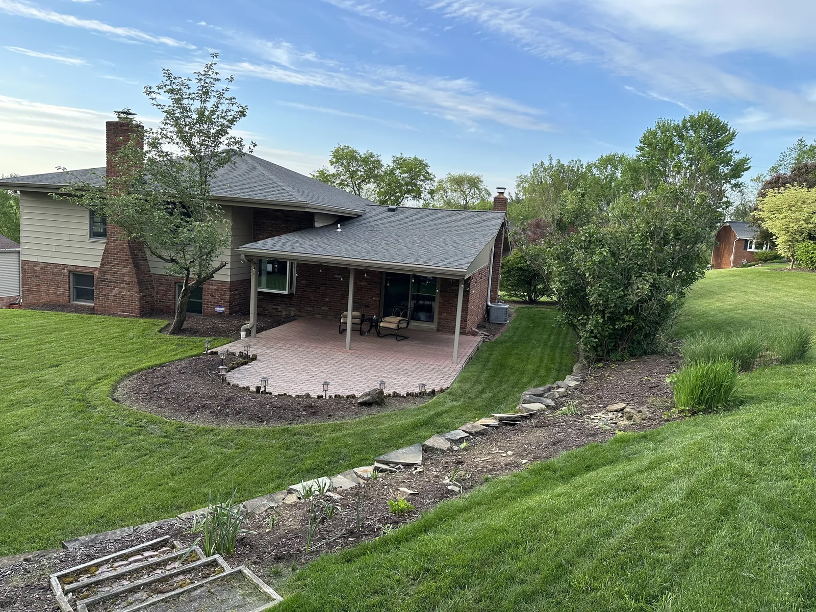 Before: the old paver patio behind the house, with a mulch bed and low stone edging around it
