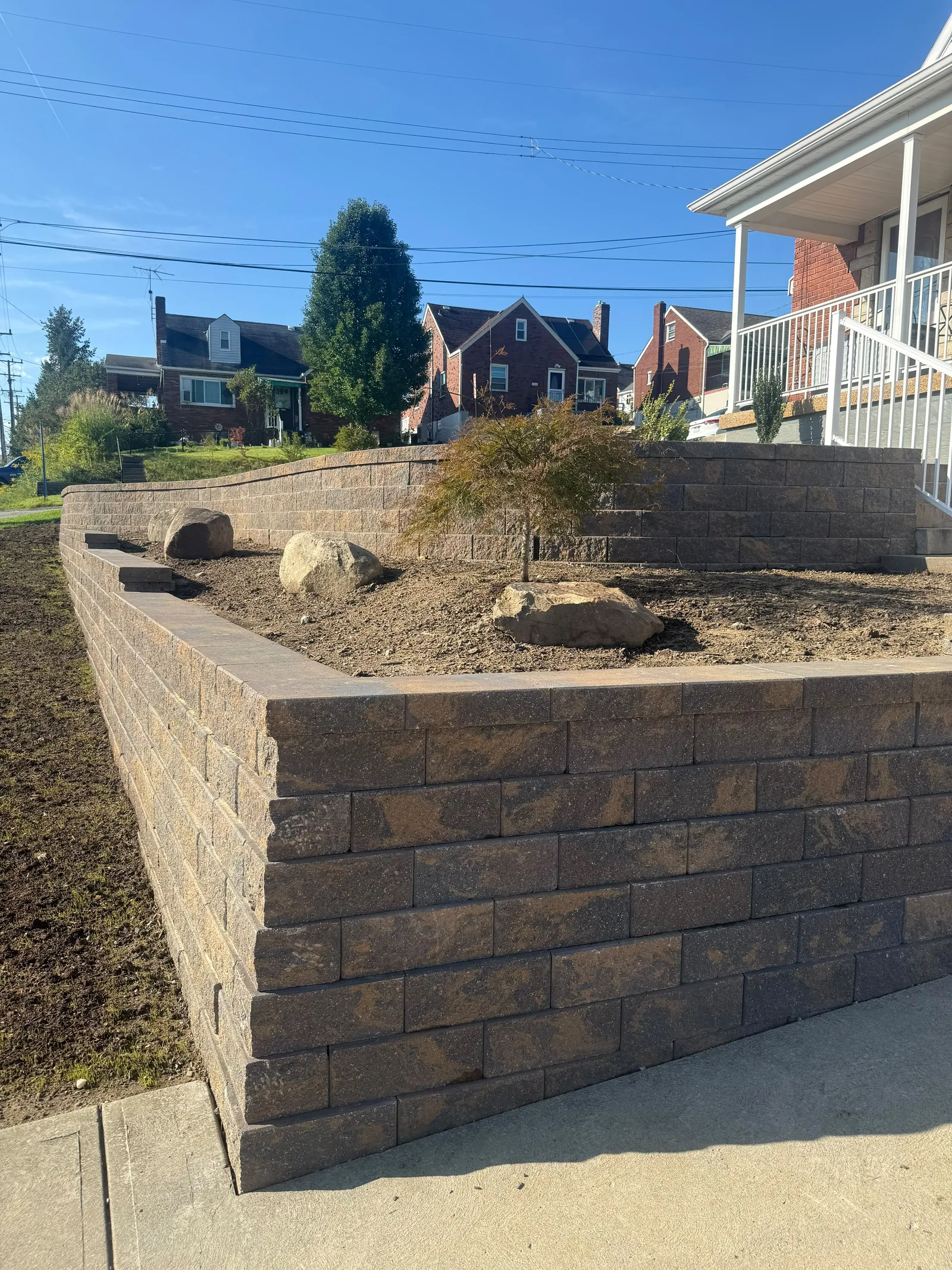 New Versa-Lok wall beside the front steps, with boulders and a small tree in the bed behind it