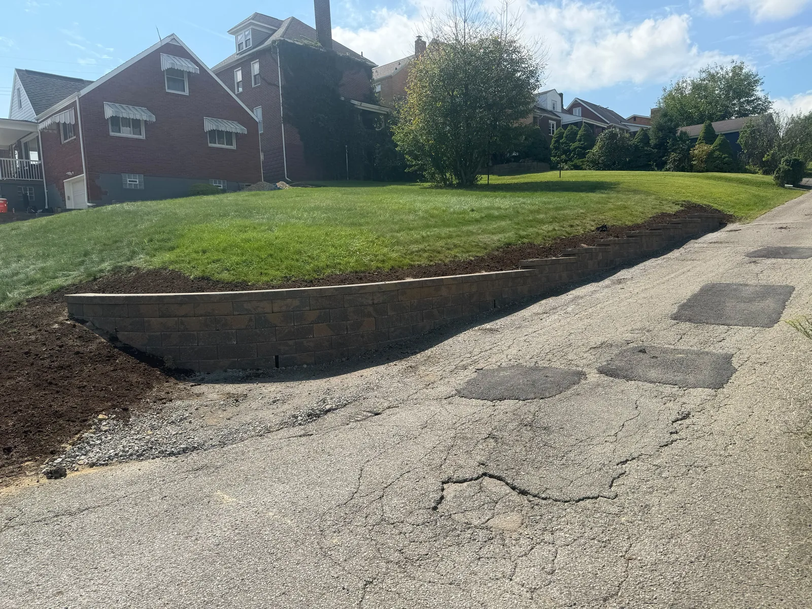 New Versa-Lok wall holding the lawn above the street, with fresh soil along its base