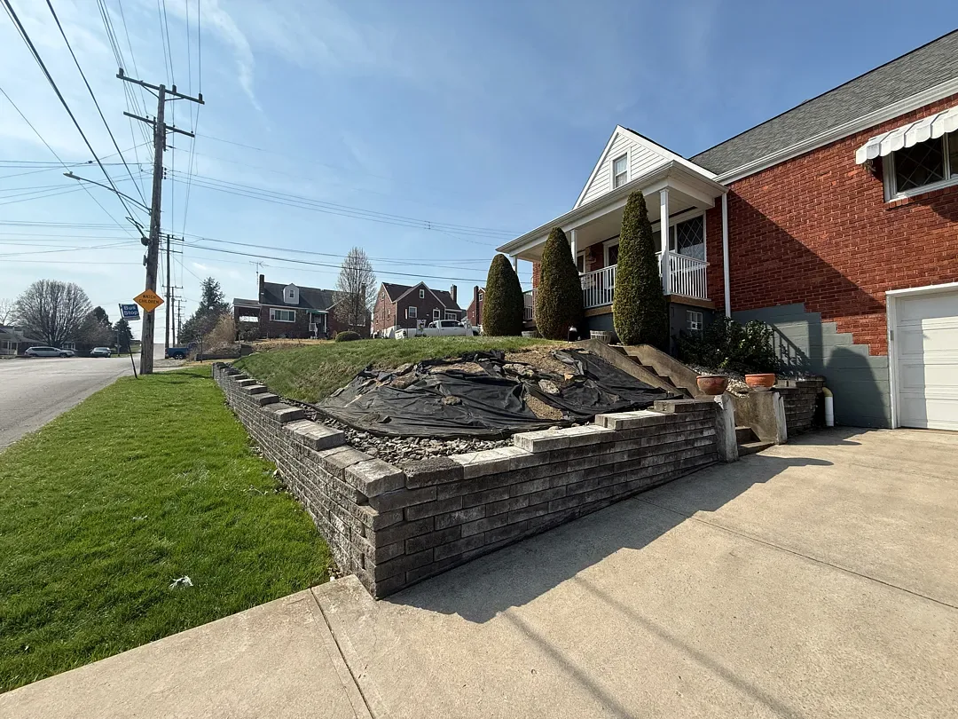 Before: the old stepped retaining wall and tarp-covered bed beside the driveway at the front of the house